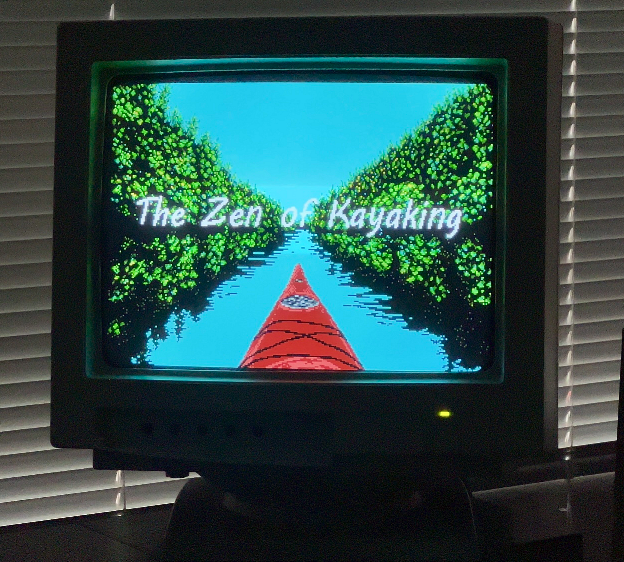 photo of the zen of kayaking splash/title art, which is a first person view on a kayak going down a river with trees either side, shown on a CRT in a dim room
